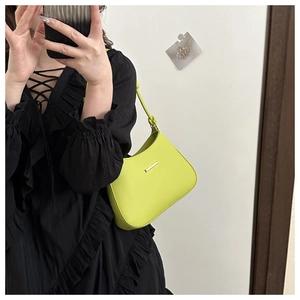 Close-up of a fluorescent green leather underarm bag with a golden metal buckle on strap