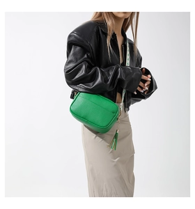 Detail of bright green pebble leather crossbody bag with side leather tassel and gold chain