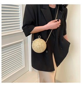 Detail of spherical hollow woven handbag with gold chain and metal ring handle