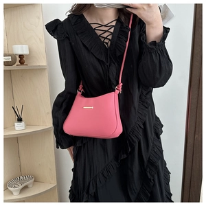 Detail of pink crossbody bag featuring gold metal hardware and knotted shoulder strap