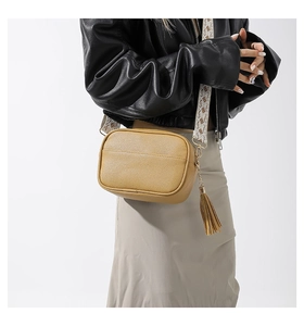 Detail of mustard yellow lychee pattern cross-body bag with jacquard strap and fringe