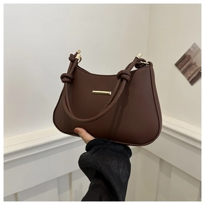 Close-up of retro dark brown handbag with leather knot handle and gold metal detail