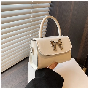 Close-up of white glossy handbag with silver metal bow and fixed top handle detail