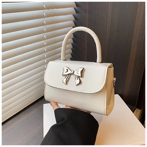 Close-up of white crossbody bag featuring a silver bow buckle and elegant top handle