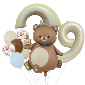 Detail of bear and rainbow foil balloons with cream number nine for birthday party decor