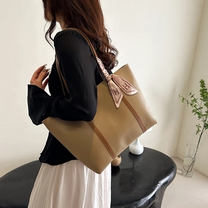Chic light brown leather tote bag with vertical stripes and silk scarf on strap