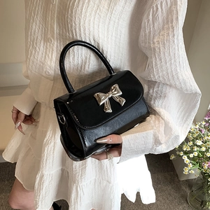 Chic black mini crossbody bag with silver metal bow detail and glossy leather finish