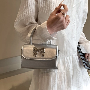 Chic silver mini flap handbag featuring a metallic bow and polished texture finish