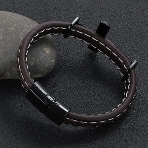 Detail of men's brown braided leather bracelet with white stitching and black magnetic clasp