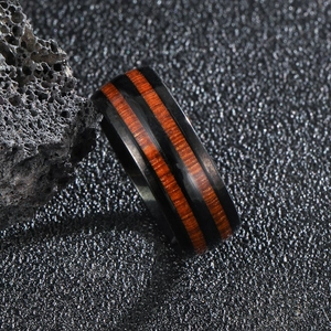Macro shot of men's black stainless steel ring with double inlaid reddish wood grain layers