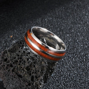 Detail view of vintage stainless steel ring with red wood inlay on dark volcanic rock