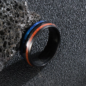 Detail of men's black titanium ring with blue opal inlay and reddish wood texture