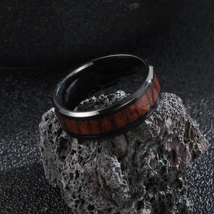Detail of polished black stainless steel ring with elegant mahogany wood grain inlay
