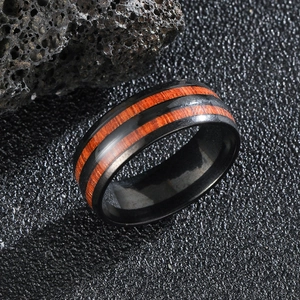 Polished black stainless steel men's ring with inlaid wood texture on dark background