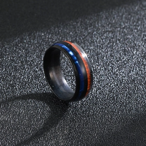 Men's black titanium ring featuring acacia wood and blue opal inlay on textured background