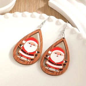 Hohl geschnittene Holzohrringe mit Weihnachtsmann-Motiv auf einer weißen Keramikplatte
