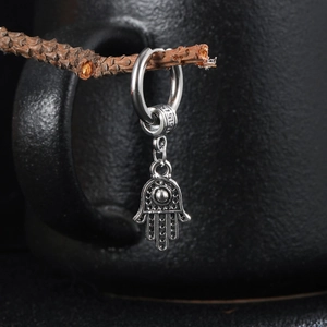 Boucle d'oreille en acier avec pendentif Main de Fatma sur support en bois naturel