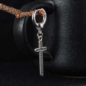 Classic silver cross earrings in titanium steel hanging on a branch with matte background