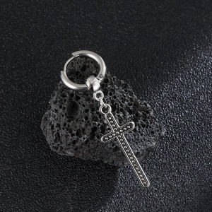 Macro shot of stainless steel cross drop earring with dotted texture on volcanic stone