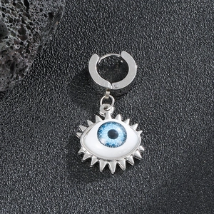 Macro detail of silver stainless steel evil eye earring on black stone surface