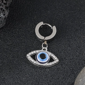 Close-up of silver evil eye earring with sparkling crystals on dark volcanic stone base