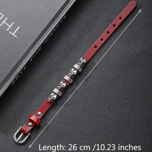 Detail of red punk leather bracelet with silver skull charms and 26cm length scale