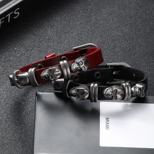 Detail of punk style leather bracelets with silver skull charms and buckle closure