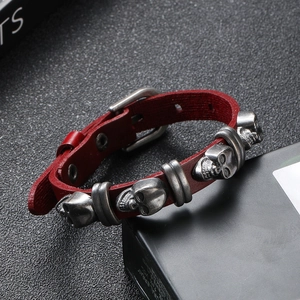 Detail of dark red leather punk bracelet with silver skull charms and buckle closure