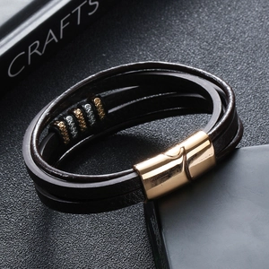 Detail of multi-layer leather bracelet with gold magnetic clasp and carved beads