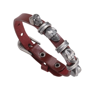 Punk style dark brown leather bracelet featuring carved silver skulls and adjustable buckle