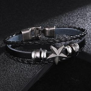 Detail of multi-layer black leather bracelet featuring a vintage metal pentagram star charm
