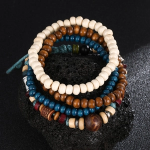 Detail view of ethnic wood bead bracelets with carved accents on dark volcanic rock