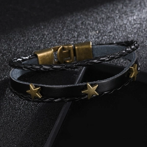 Detail of woven black leather bracelet with bronze star charms and magnetic clasp
