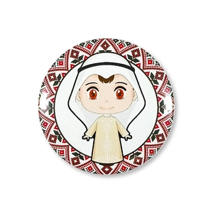 Detail of round tinplate badge featuring a cartoon boy in traditional Arab dress and patterns