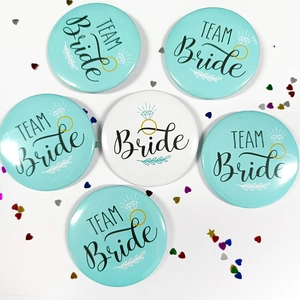 Flat lay of 6 round Bride and Team Bride tinplate badges with diamond ring graphics