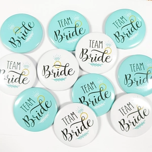 Flat lay of Team Bride wedding badges with mint green floral and gold ring design