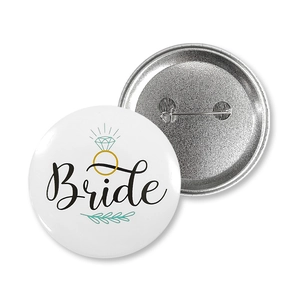 Close-up of Bride tinplate badge showing the safety pin back and white front design