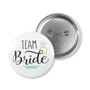 Macro detail of Team Bride tinplate badge showing both front design and pin backing