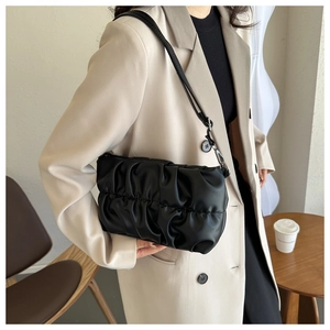 Dettaglio borsa a spalla nera a pieghe indossata con un elegante blazer beige oversize