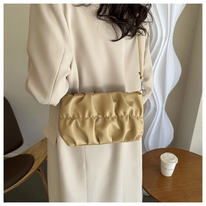 Détail d'un sac bandoulière plissé crème avec texture souple et fine bandoulière d'épaule