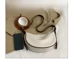 Detailed comparison showing hobo bag size next to a smartphone with brown shoulder strap