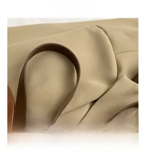 Detail shot of the durable brown leather handles and premium stitching on khaki canvas tote