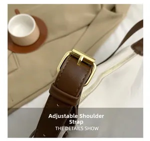 Detail of adjustable brown leather shoulder strap with gold buckle on a white tote bag
