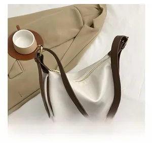 Detail of white moon bag with brown adjustable strap and elegant gold metal buckle