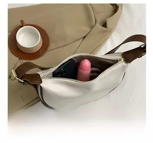 Detail of white leather crescent bag showing interior space with phone and lipstick
