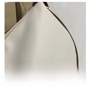 Detailed close-up of cream leather texture with contrast dark brown stitched edges