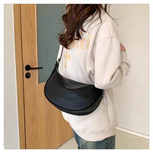 Detail of a black crescent moon shoulder bag with adjustable strap and gold buckle