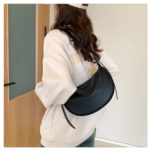 Detailed back view of a black crescent crossbody bag worn by a model in a minimalist setting