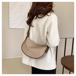 Detail of beige crescent shoulder bag with dark brown strap on tweed jacket