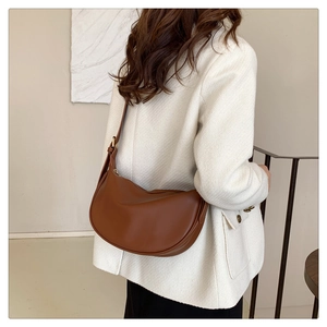 Detailed side view of brown leather half-moon hobo bag with vintage gold metal buckle